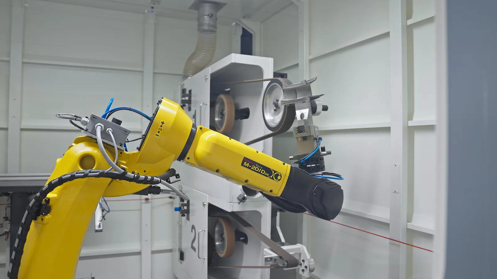 Industrial robot pressing a curved metal blade against a belt grinding machine