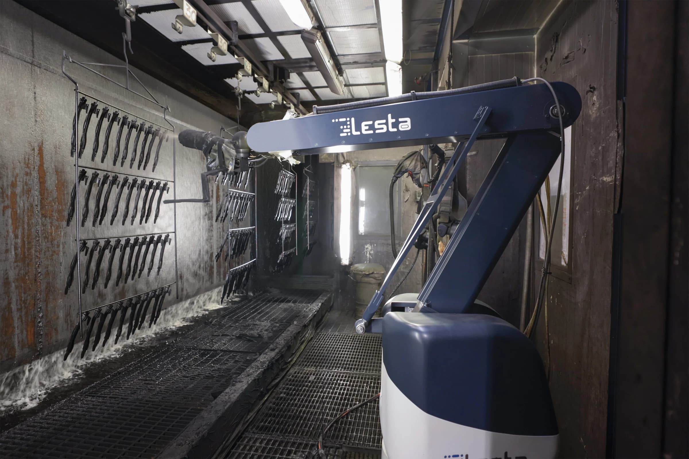 Industrial robotic painting arm coating rows of suspended components on a manufacturing line